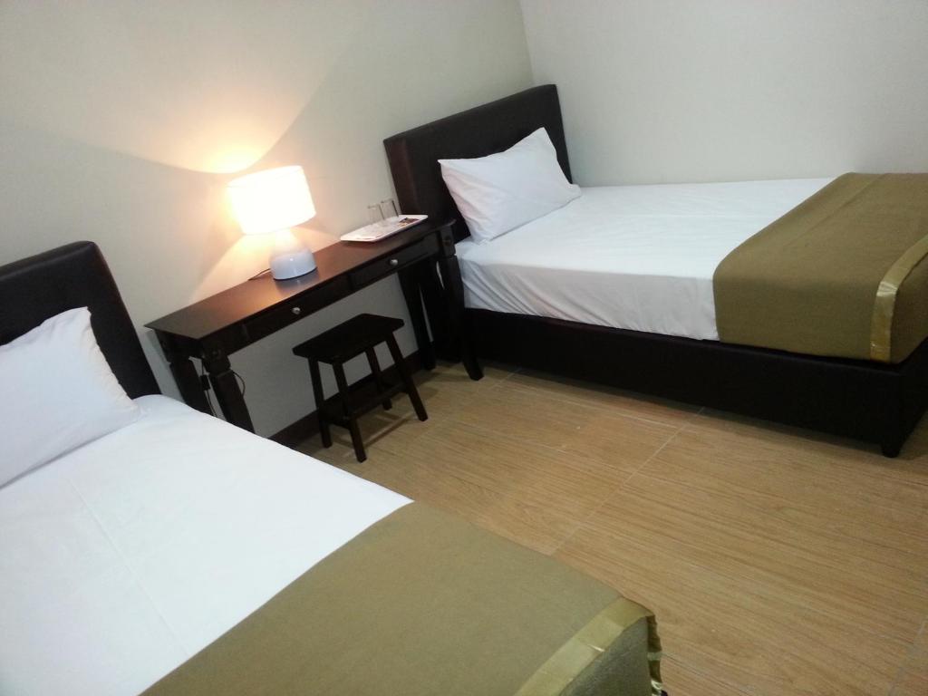 a hotel room with two beds and a desk with a lamp at Fargo Boutique Hotel in Kuantan