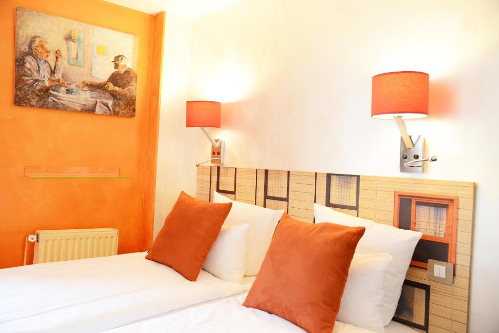 パリにあるオテル マラーのベッドルーム1室(オレンジと白の枕が備わるベッド1台付)