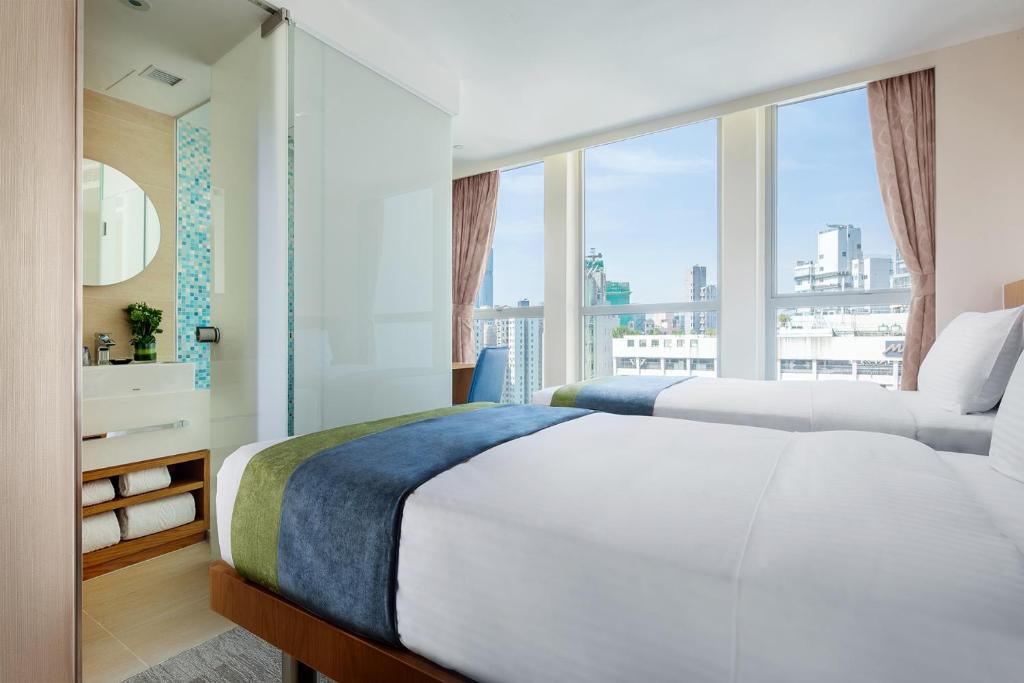 a bedroom with two beds and a large window at Summit View Kowloon in Hong Kong