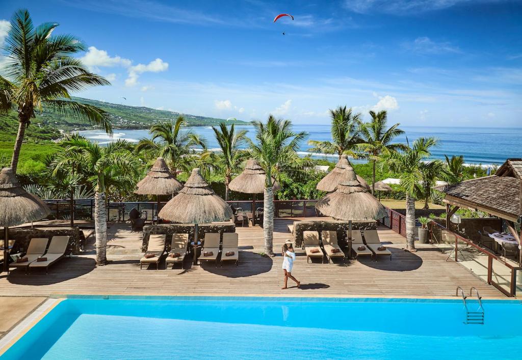 a woman walking by a pool at a resort at Iloha Seaview Hotel in Saint-Leu