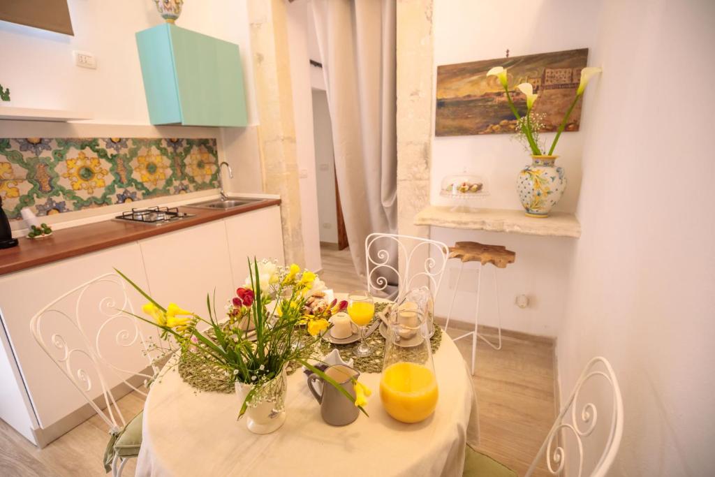 - une table blanche avec des fleurs dans la cuisine dans l'établissement "Il principio di Archimede"guest & art house, à Syracuse