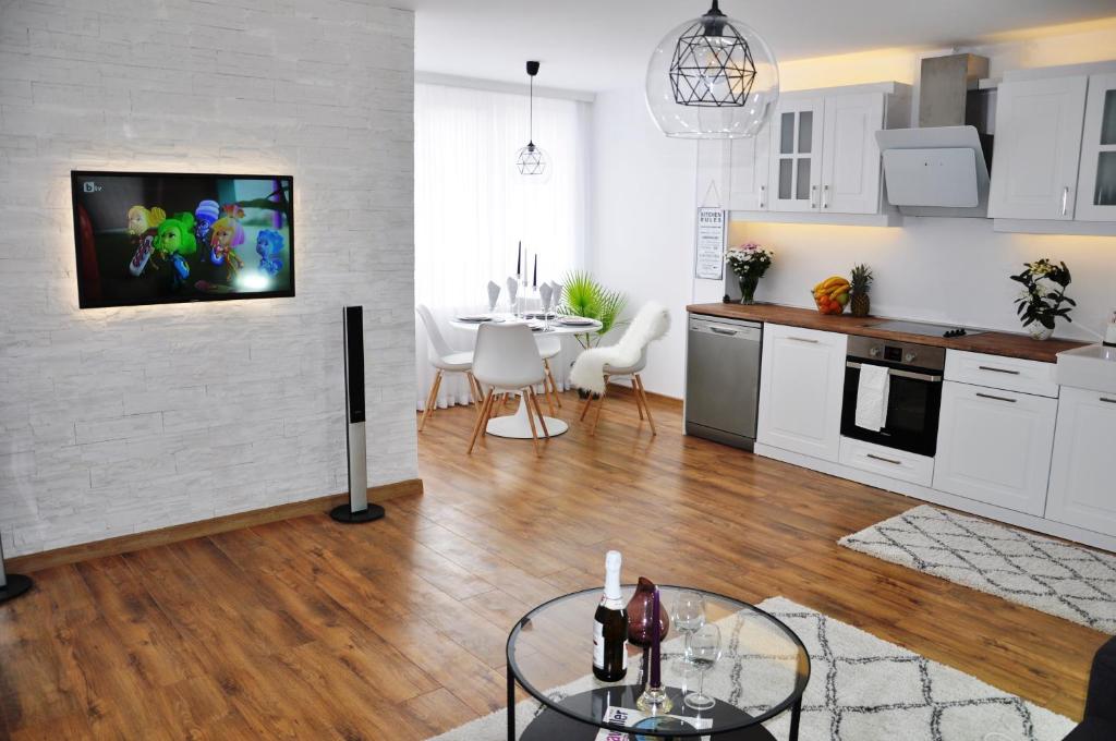 a kitchen and living room with a table and a tv at Lux Apartment in Pazardzhik