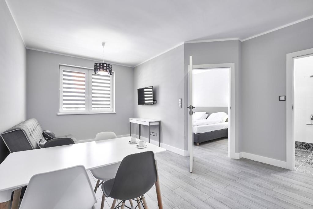 a white room with a table and chairs and a bed at Apartamenty Między Jeziorami in Olsztyn