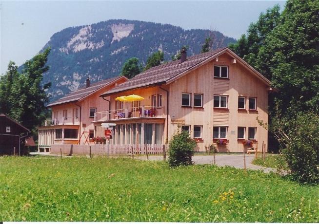 une grande maison dans un champ à côté d'une montagne dans l'établissement Ferienwohnungen Schantl, à Schoppernau