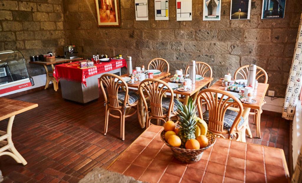 a restaurant with a table and chairs with a bowl of fruit at Villa Rock Stop Falls Gigiri in Nairobi