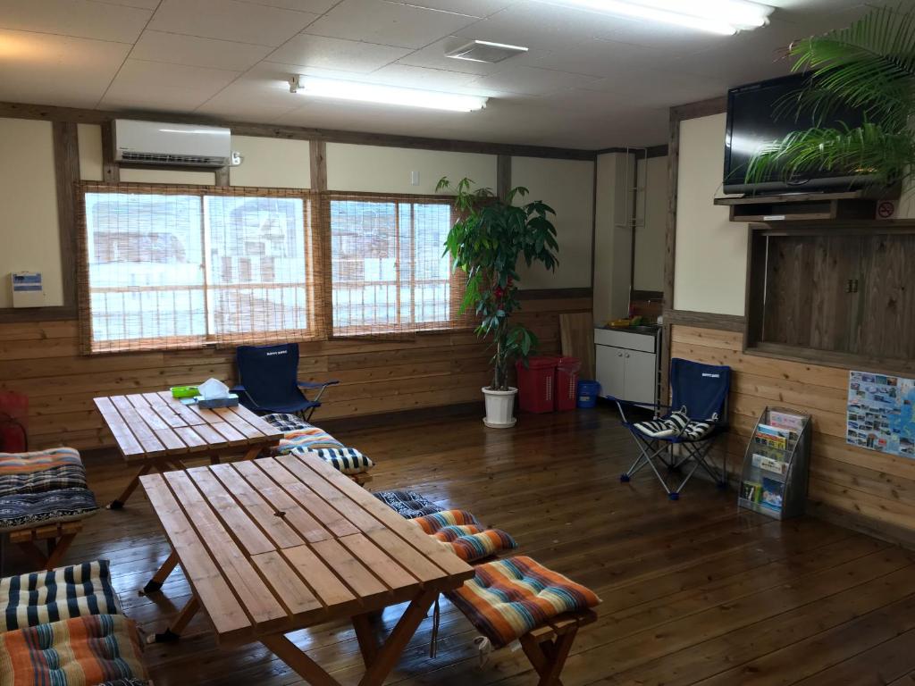 a room with tables and chairs and a flat screen tv at Guesthouse Minami in Setouchi