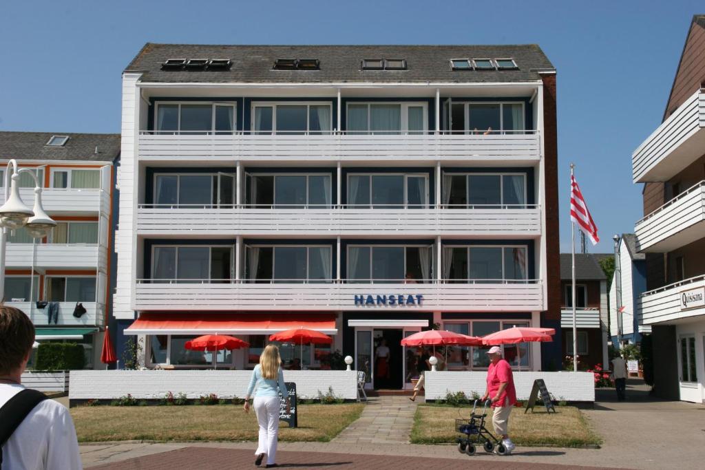 pessoas a caminhar em frente a um hotel com guarda-chuvas vermelhos em Hanseat em Helgoland