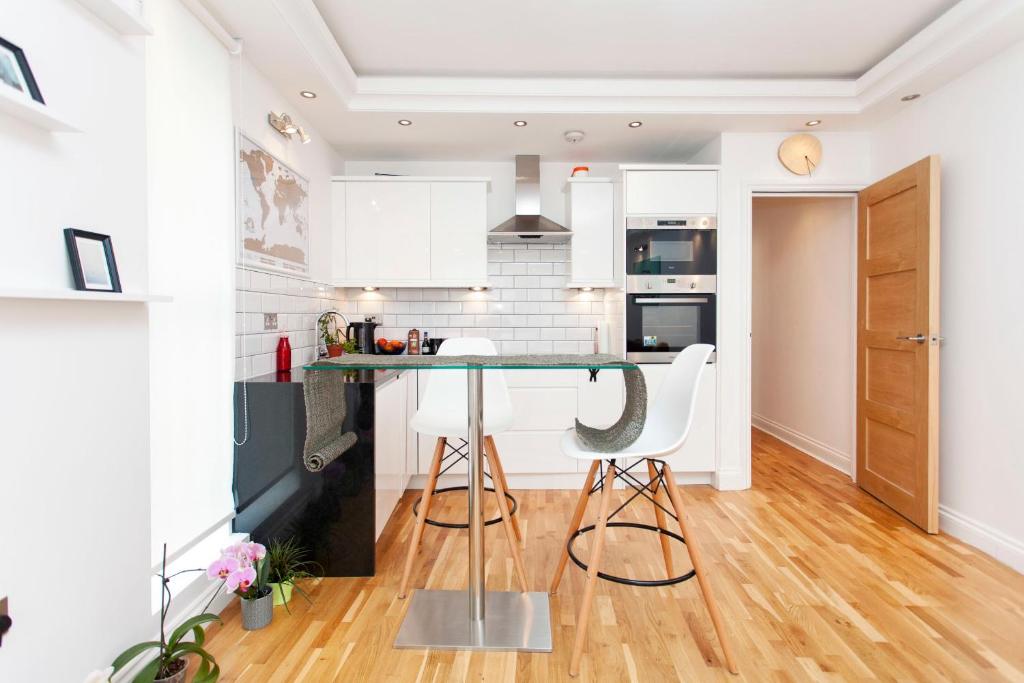 a kitchen with white cabinets and a green counter top at Italianflat - Stamford Bridge in London