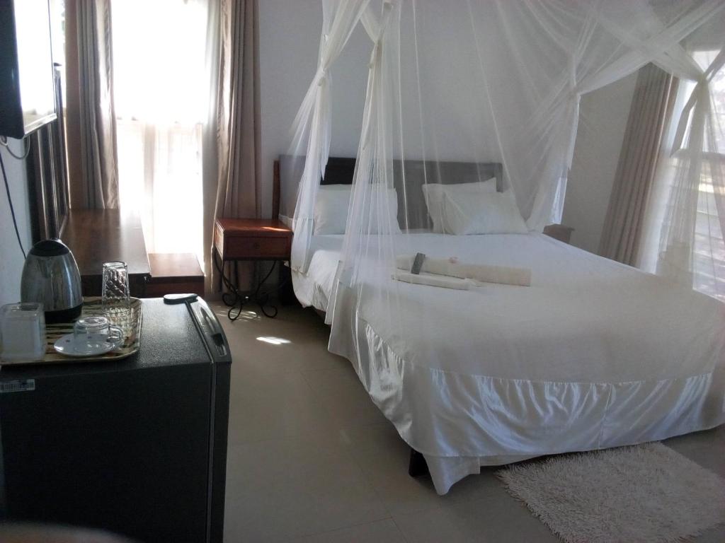 a bedroom with a white bed with a canopy at Kuku Royal Lodge in Ndola