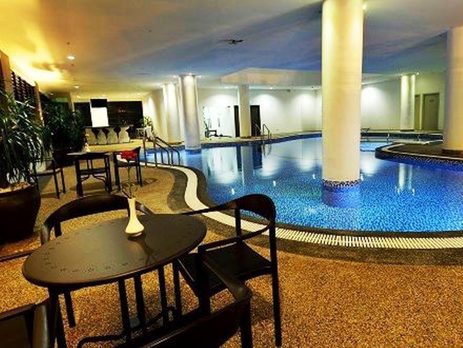 a large swimming pool with a table and a table at Holiday Villa Hotel & Suites Kota Bharu in Kota Bharu