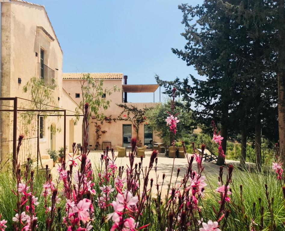 een tuin met roze bloemen voor een gebouw bij Battimandorlo in Noto