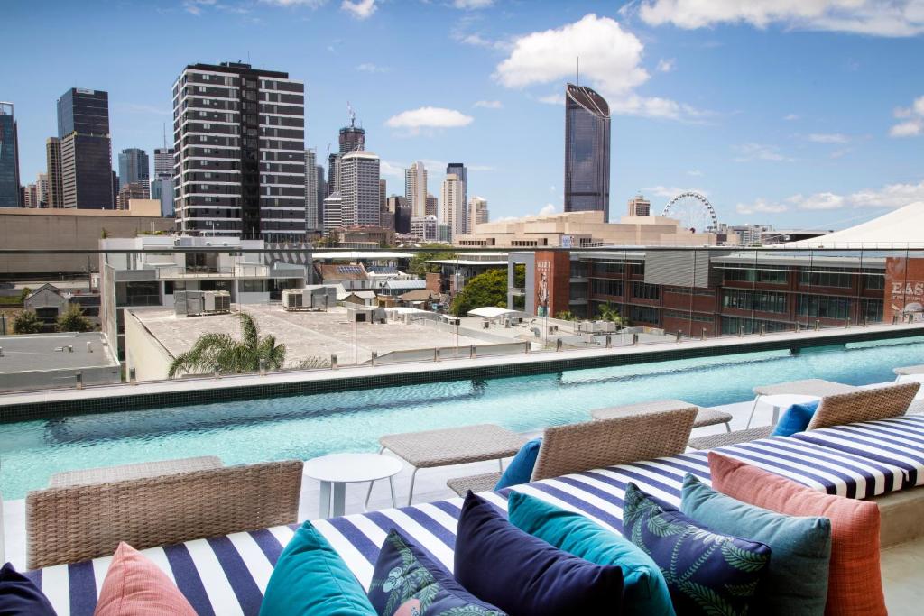 a pool with chairs and a view of a city at Ivy and Eve Apartments by CLLIX in Brisbane
