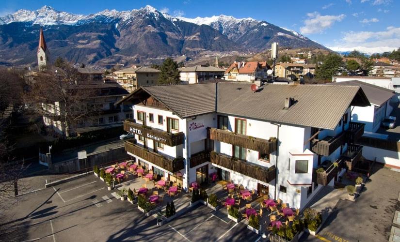 uma vista aérea de um edifício com montanhas ao fundo em Hotel Daniela em Merano