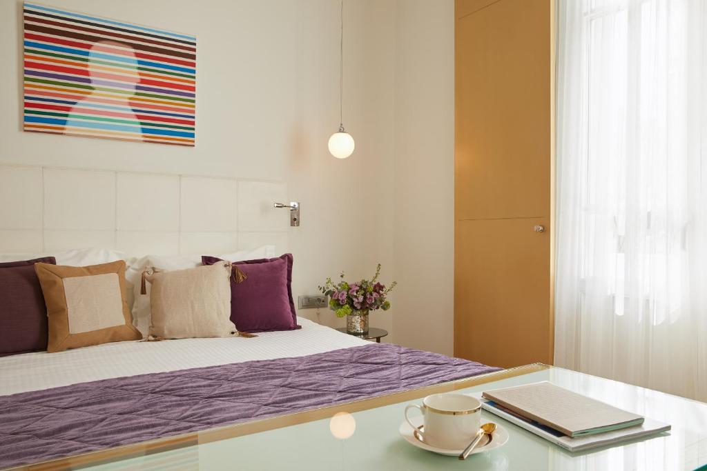 a bedroom with a bed with purple sheets and a table at The Excelsior - Small Luxury Hotels of the World in Thessaloniki