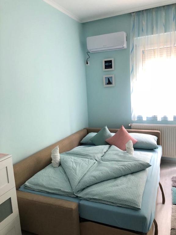 sypialnia z łóżkiem z niebieskimi ścianami i oknem w obiekcie Aquamarin Studio Apartman w Siófoku