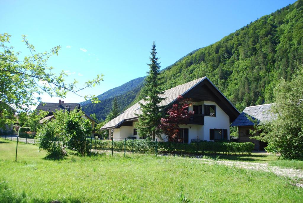 a house in a field with mountains in the background at Apartments Trata in Kranjska Gora