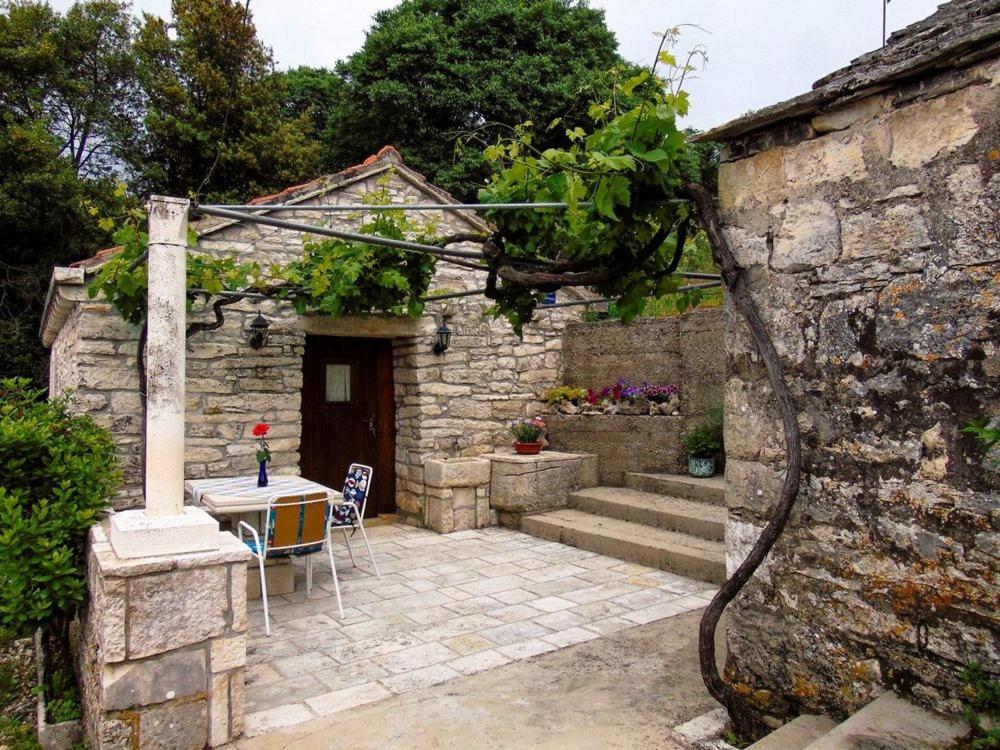 een stenen huis met een patio en een tafel bij Mario (RADE) in Korčula