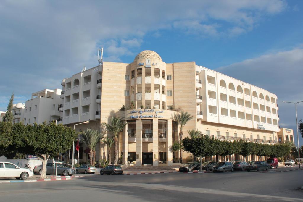 ein großes Gebäude mit Autos auf einem Parkplatz in der Unterkunft El Kantaoui Center in Sousse
