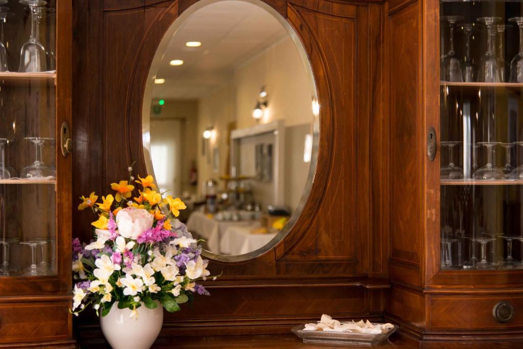 un bagno con specchio e vaso di fiori di Hotel Elisabetta a Sestri Levante