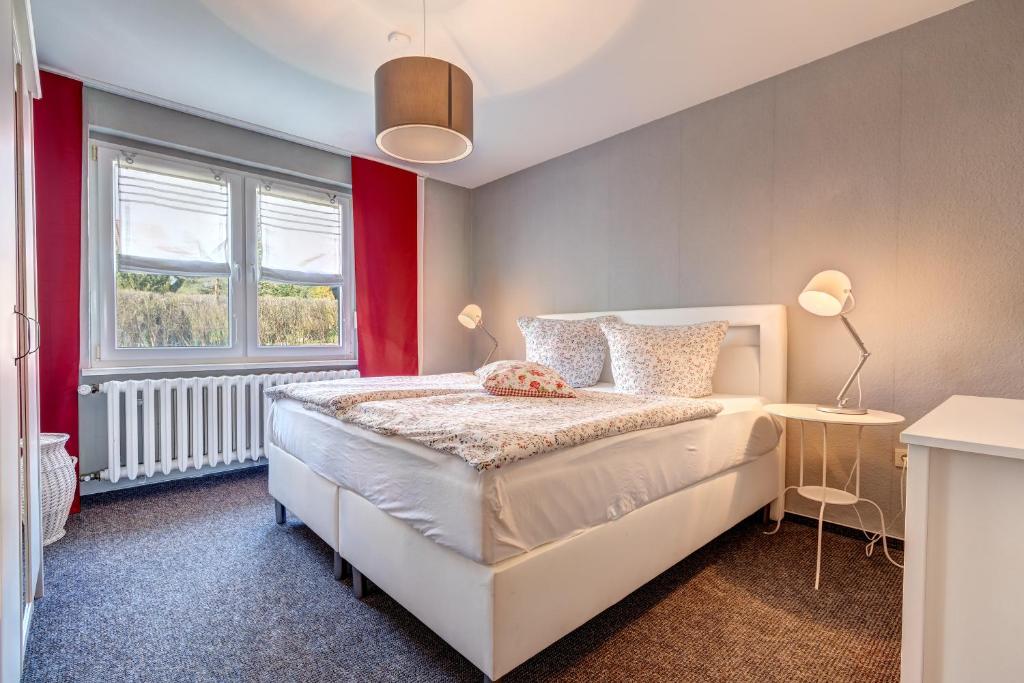 1 dormitorio con cama blanca y pared roja en Haus N°9 en Hohendorf