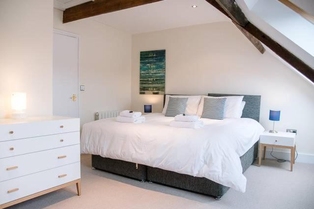 a bedroom with a white bed and a white dresser at Serendipity, an apartment on the high street! in Aldeburgh
