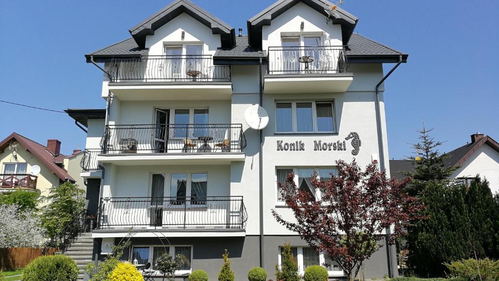 a white building with balconies and a sign on it at Konik Morski in Władysławowo