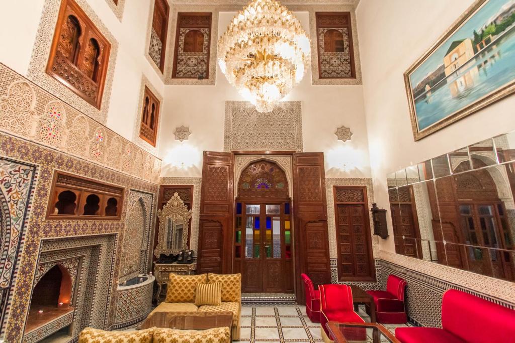 - un hall avec des chaises rouges et un lustre dans l'établissement Riad Fes Andalucia, à Fès
