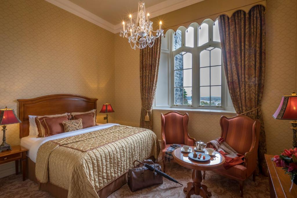 a bedroom with a bed and a table and a chandelier at Kilronan Castle Hotel & Spa in Ballyfarnon