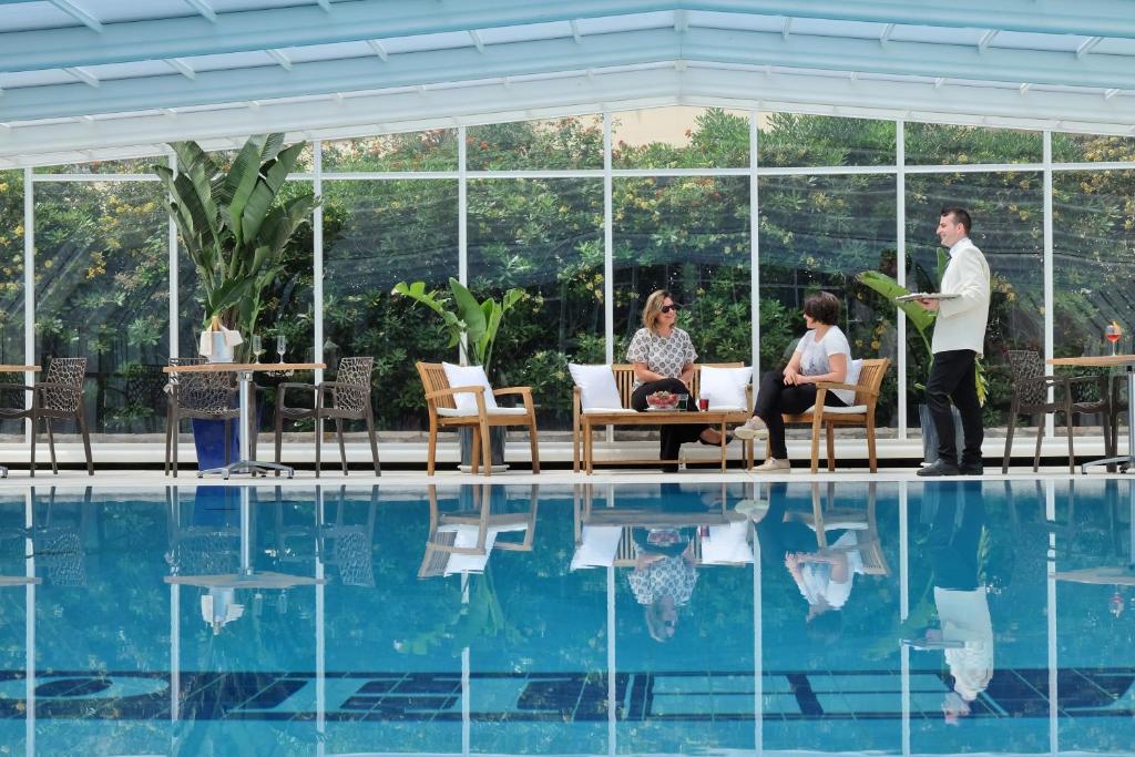 a man standing in front of a pool with people sitting at Joli Park Hotel - Caroli Hotels in Gallipoli