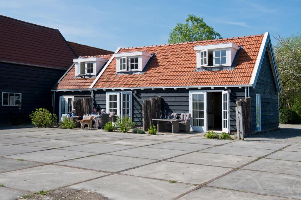 ミデルブルフにあるGastenverblijven boerderij Het Driespanのオレンジ色の屋根とパティオ付きの家