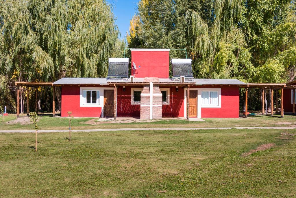 a red and white house with trees in the background at Cabañas El Remanso in Tupungato