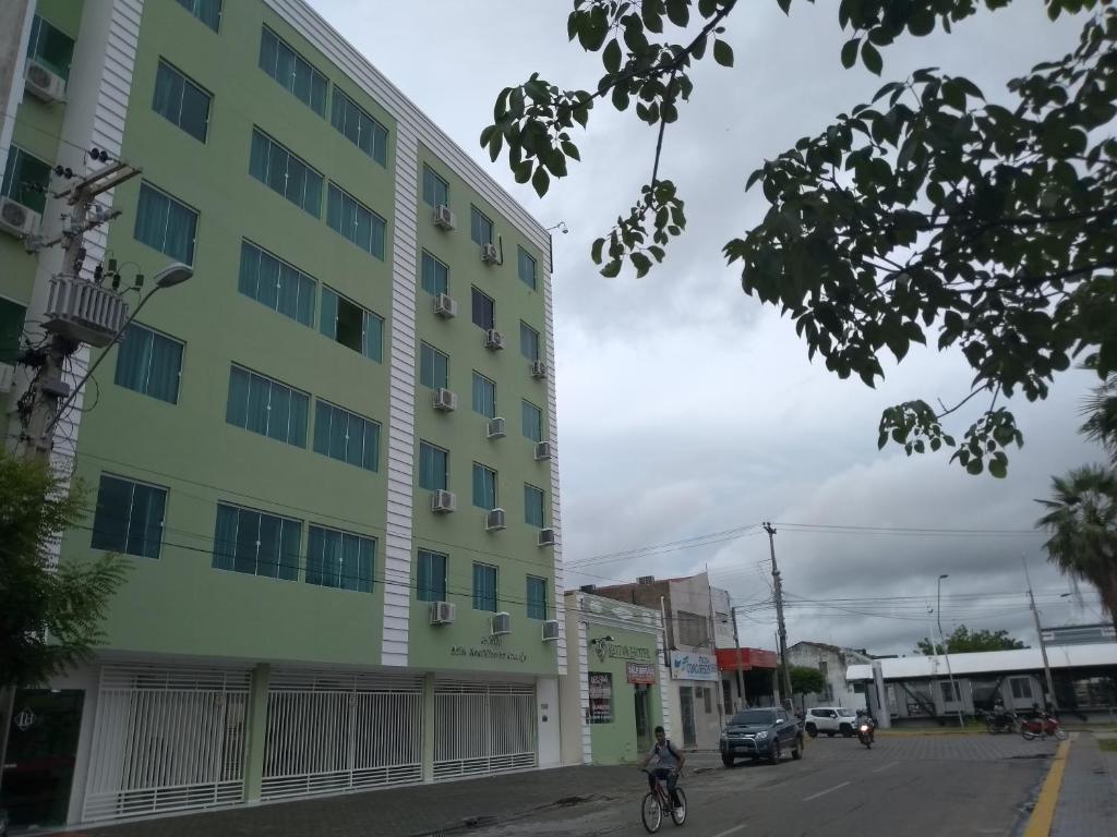 a person riding a bike in front of a building at Hotel Letiva Arco in Sobral