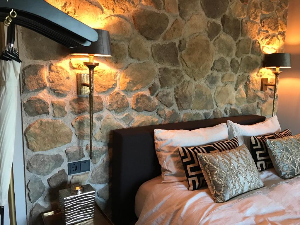 a bedroom with a stone wall and a bed with pillows at Chill-out in Nieuwe Wetering