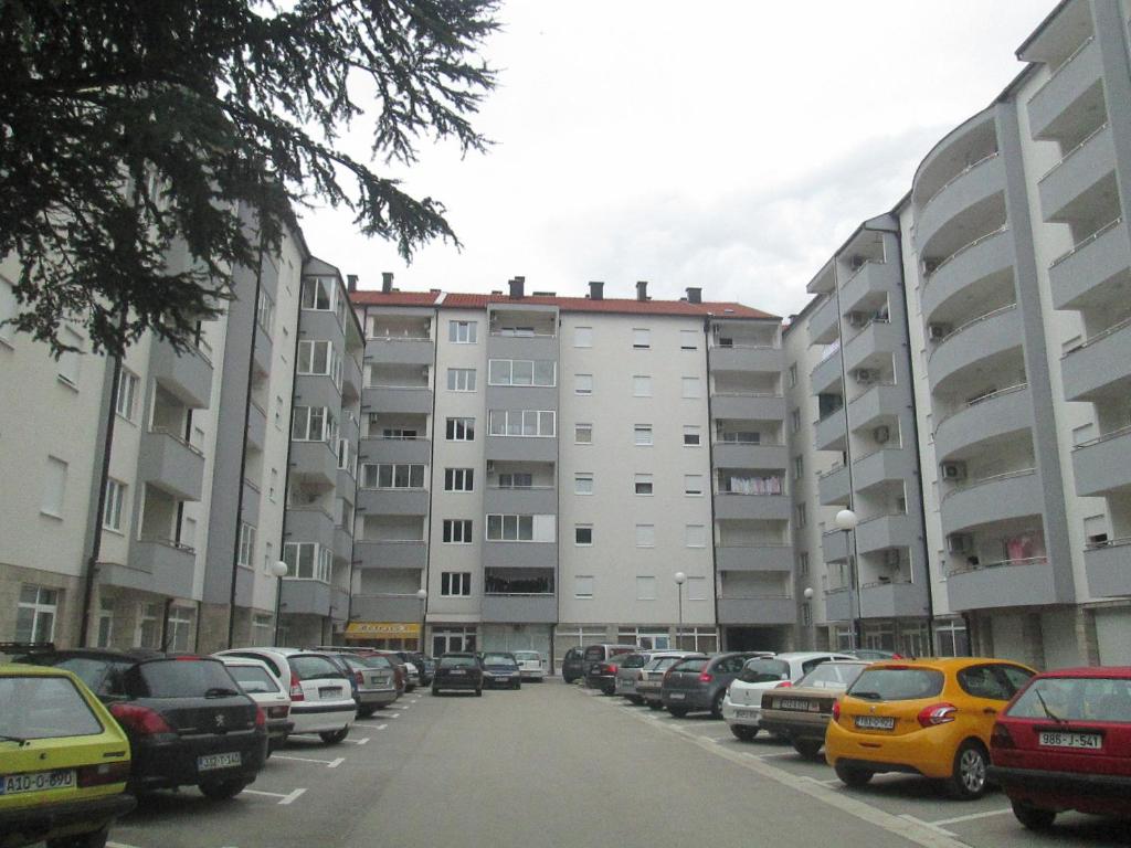 een parkeerplaats met auto's voor gebouwen bij Apartman G&A in Trebinje