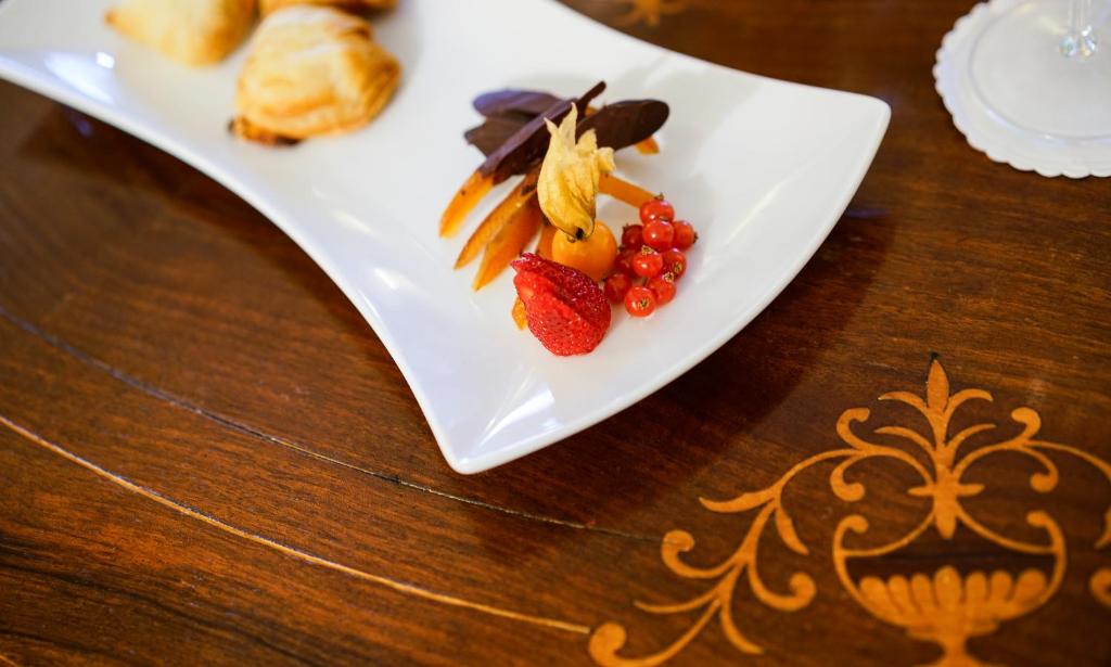 a white plate with fruit and vegetables on a table at Hotel Villa Cimbrone in Ravello