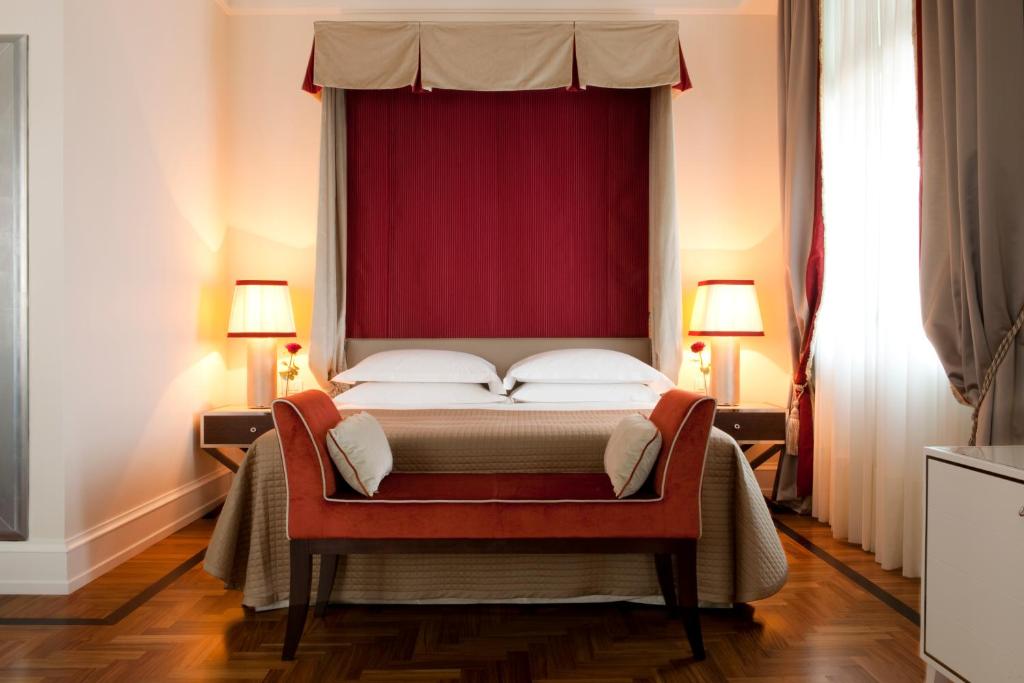 a bedroom with a large bed with a red curtain at Savoia Excelsior Palace Trieste - Starhotels Collezione in Trieste