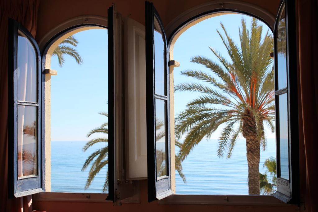 a window view of a palm tree and the ocean at La Santa María in Sitges