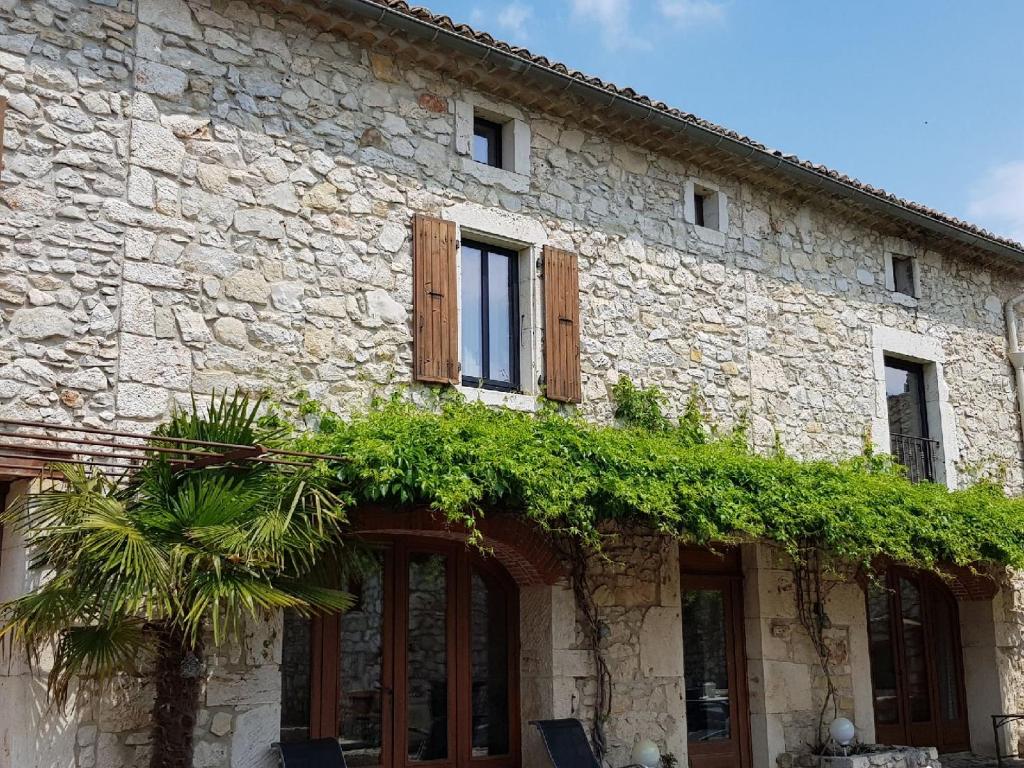 um edifício de pedra com janelas e plantas em La bastide Maë em Saint-Remèze