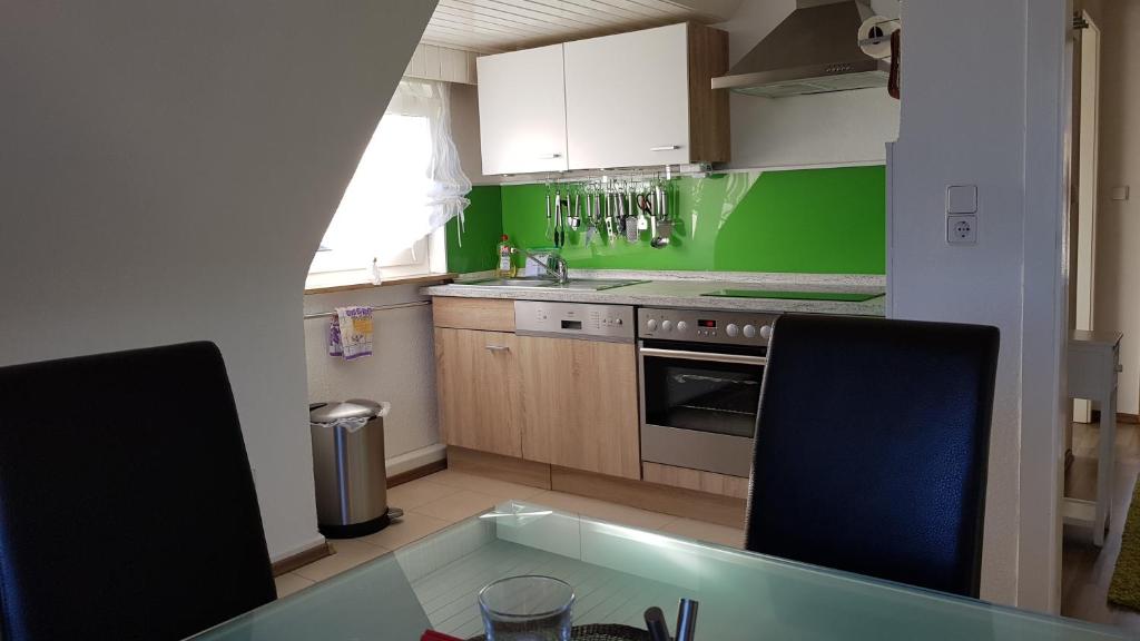 - une cuisine avec des murs verts, une table et deux chaises dans l'établissement Ferien- Messewohnung nähe Köln-Messe Flughafen Bonn, à Rösrath