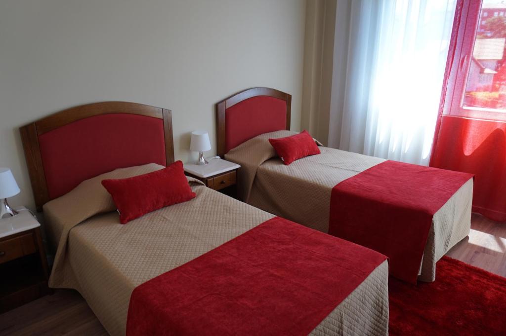 een hotelkamer met 2 bedden met rode kussens bij Comfort Tua in Mirandela
