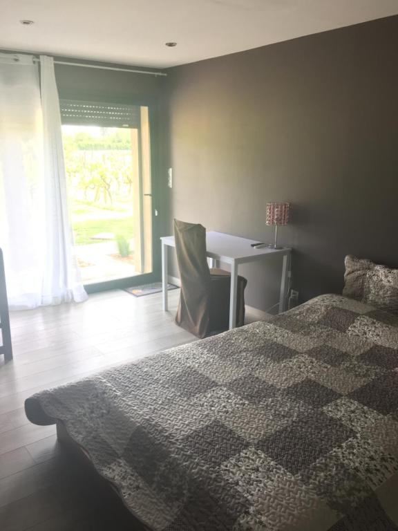 a bedroom with a bed and a desk and a window at Safranière des Sorgues in Le Thor