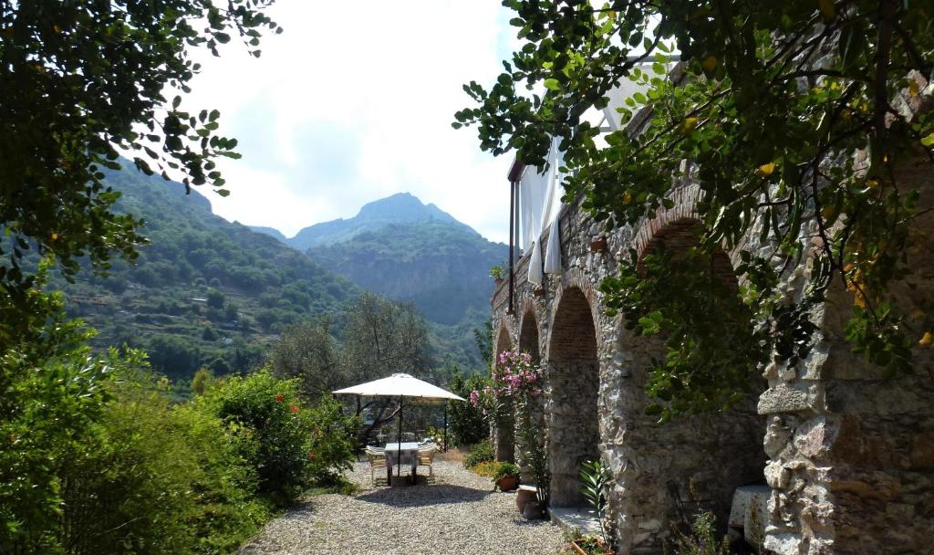 a stone wall with a table and an umbrella at Casale Praia in Letojanni