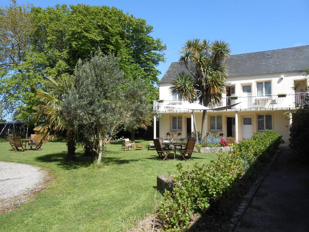 uma casa com um quintal com cadeiras e árvores em La Demeure du Perron em Quettehou