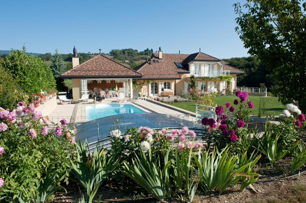 a house with a swimming pool and flowers at Le Lierre B&B in Genolier