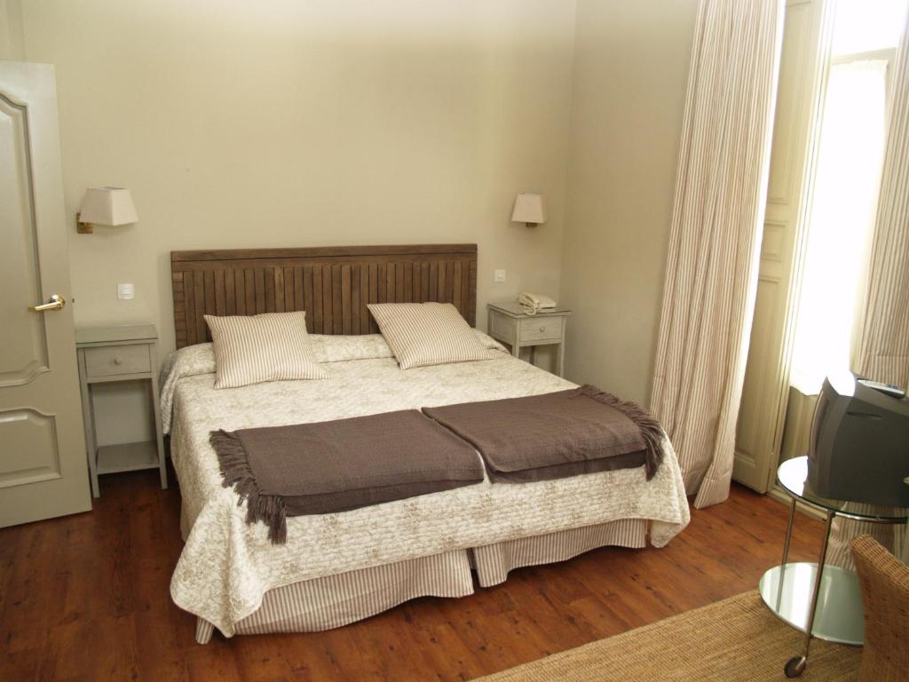 1 dormitorio con 1 cama, 2 mesas y TV en Hotel Roma, en La Granja de San Ildefonso