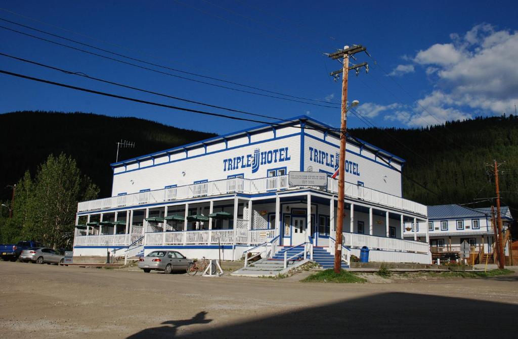 a large white building with cars parked in front of it at Triple J Hotel in Dawson City