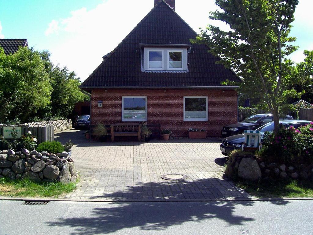 ein rotes Backsteinhaus mit einem davor geparkt in der Unterkunft Haus Kamp in Tinnum