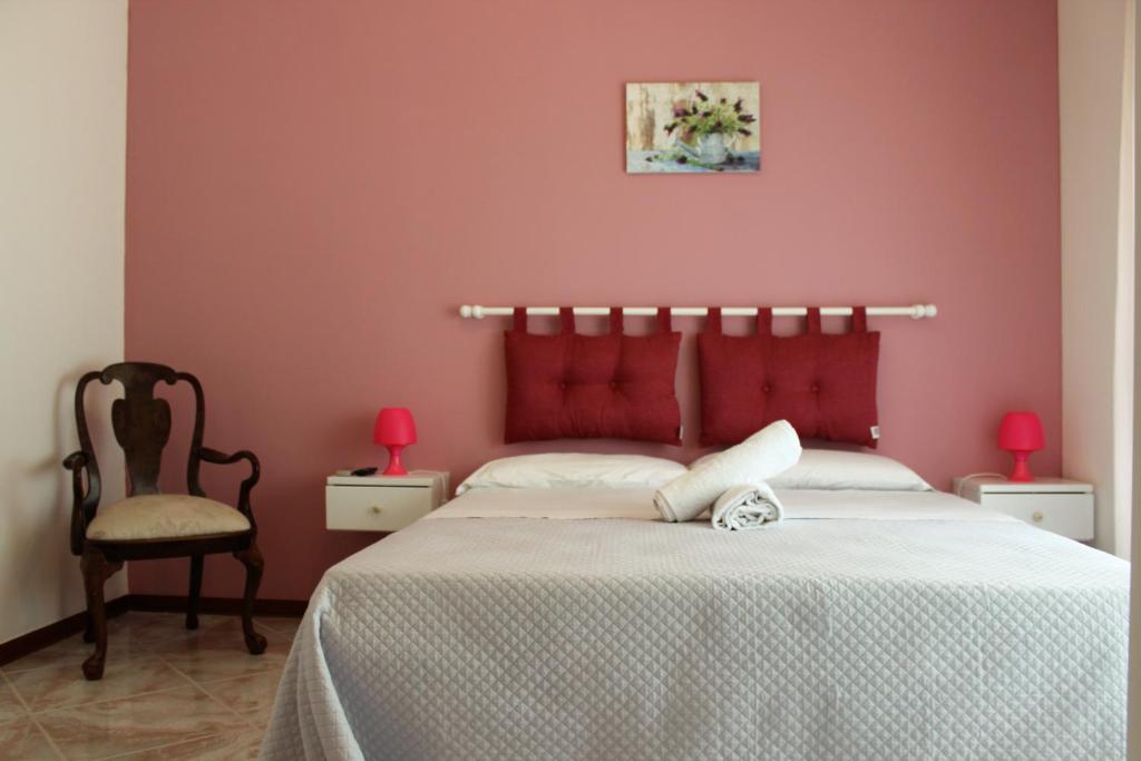カステッランマーレ・デル・ゴルフォにあるCasa Chiarenzaのピンクの壁のベッドルーム(ベッド1台、椅子1脚付)