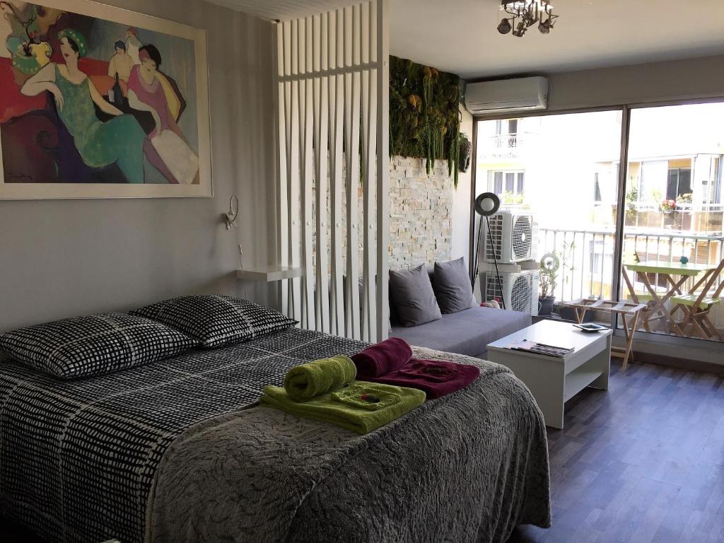 a bedroom with a bed and a living room at 1 Chambre, 1 P'tit dèj', 1 Sourire in Montpellier