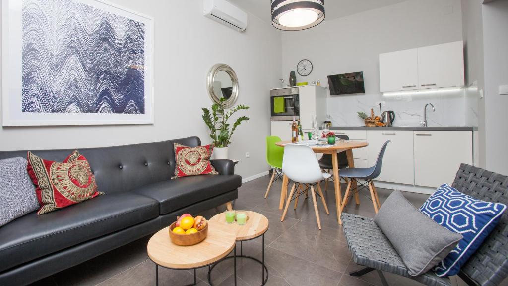 un salon avec un canapé noir et une cuisine dans l'établissement apartman ami, à Split